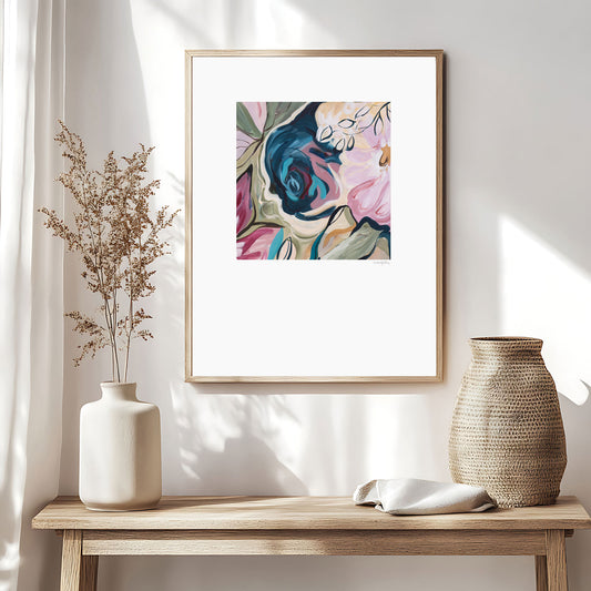 Contemporary colourful abstract floral paper art print with a big white border around it. Framed in a natural frame and hanging in a neutral modern living room.