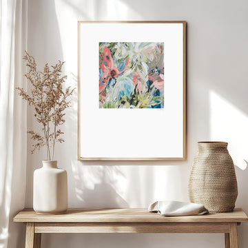 Colourful abstract flower paper wall art print in pastel shades of pink, blue, green, white and brown. Simple floral shapes layered in an expressionist style. Big white border surrounding the square flower design. Framed in a natural frame and hanging in a modern neutral lounge room.