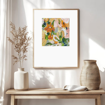 Modern abstract flower wall art print in soft shades of orange, green, warm yellow. Layered flower petals in an expressive style in a square format. Big white border surrounds the design. Framed in a natural frame and hanging on a contemporary neutral living room wall.