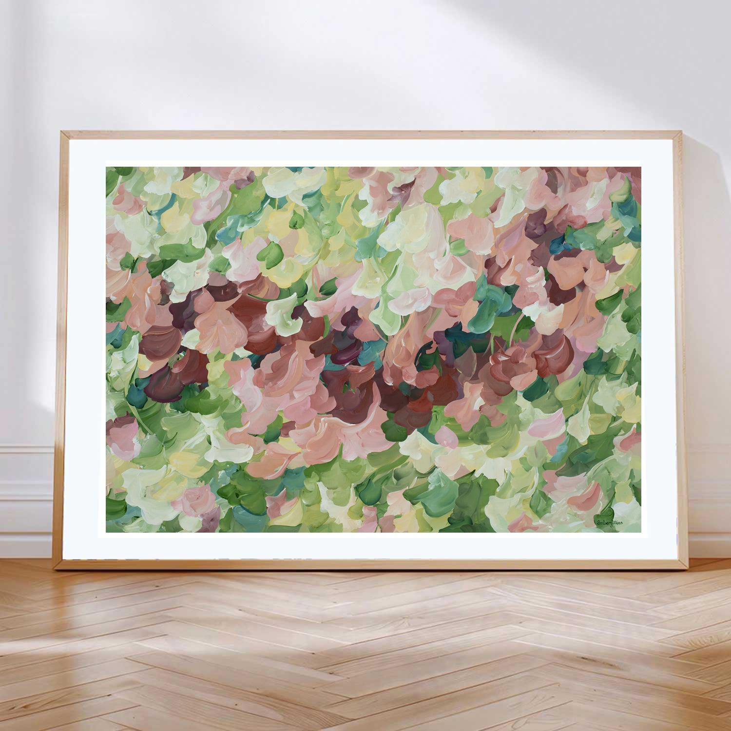 Modern nature art print in contemporary colours of warm brown and pinks and natures green. Contemporary impressionist simple style. Framed in a natural frame and leaning against a living room wall.