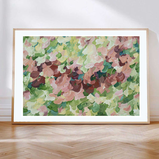Modern nature art print in contemporary colours of warm brown and pinks and natures green. Contemporary impressionist simple style. Framed in a natural frame and leaning against a living room wall.