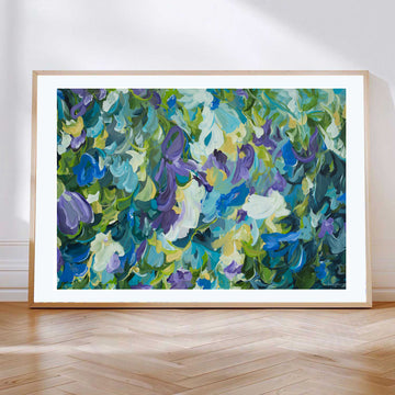 Contemporary abstract floral fine art print in blue, purple, green and yellow. Leaning against a living room wall with a natural frame.