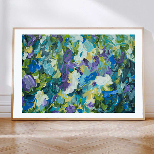 Contemporary abstract floral fine art print in blue, purple, green and yellow. Leaning against a living room wall with a natural frame.