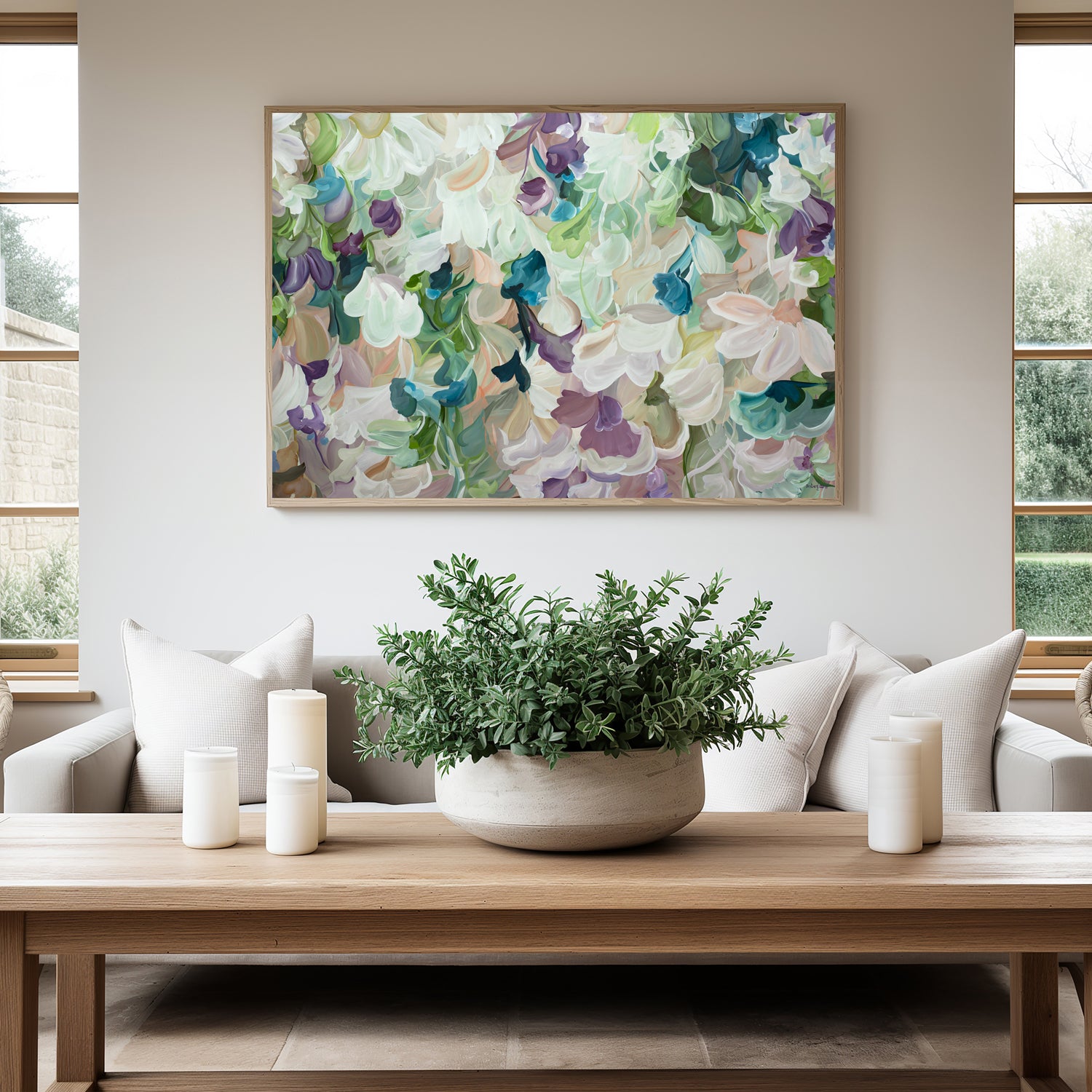 Modern abstract flower art print in pastel shades of green, pink, apricot and turquoise. Hanging in a modern neutral living room with a white sofa.