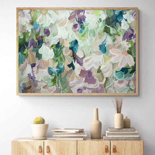 Modern abstract flower art print in pastel shades of green, pink, apricot and turquoise. Hanging in a living room with a natural frame.