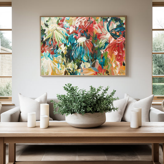 Bold and bright colourful abstract wild flower canvas art print in reds, turquoise and ochre yellows in a natural frame. Hanging in a modern living room.