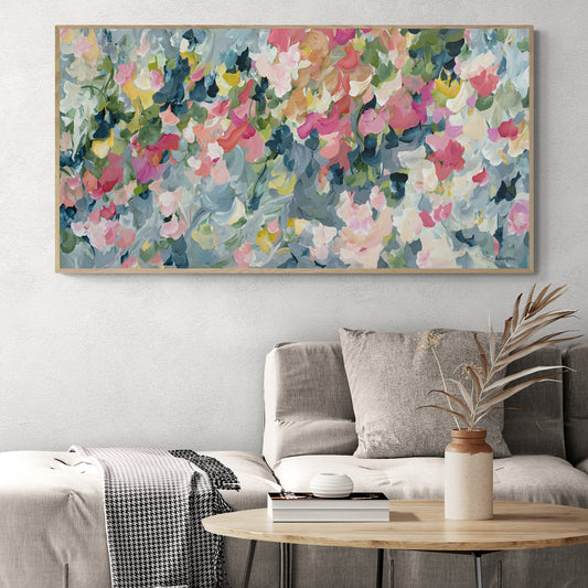Contemporary impressionist style abstract art print inspired by flower petals and organic shapes of a flower garden. Modern colour palette of blue grey, pink and green. Framed in a natural frame hanging in a neutral modern lounge room.