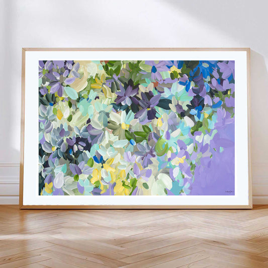 Modern impressionist style abstract flower art print in purple and yellow and white. Leaning against a wall with a natural frame.