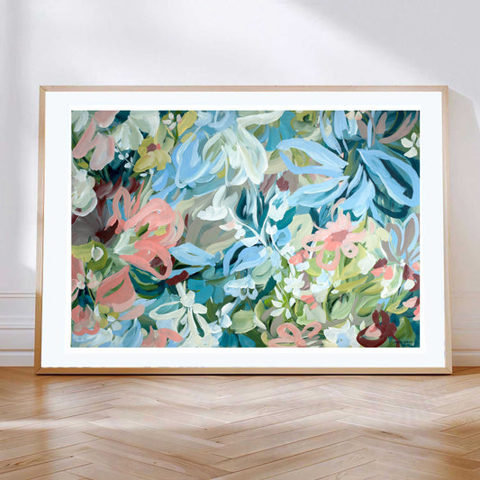 Pretty abstract floral fine art paper print in pastel shades of baby blue, salmon pinks, turquoise and greens. With a natural frame leaning against a wall.