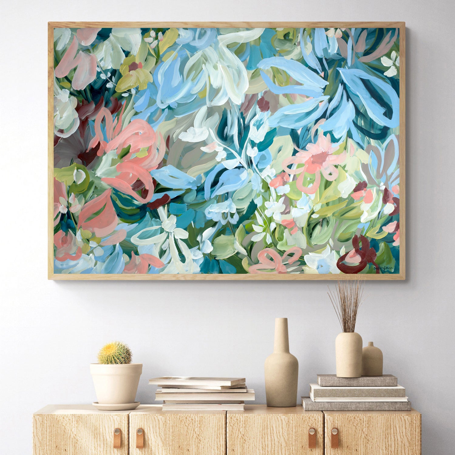Pretty abstract floral fine art canvas print in pastel shades of baby blue, salmon pinks, turquoise and greens. With a natural frame hanging against a living room wall.