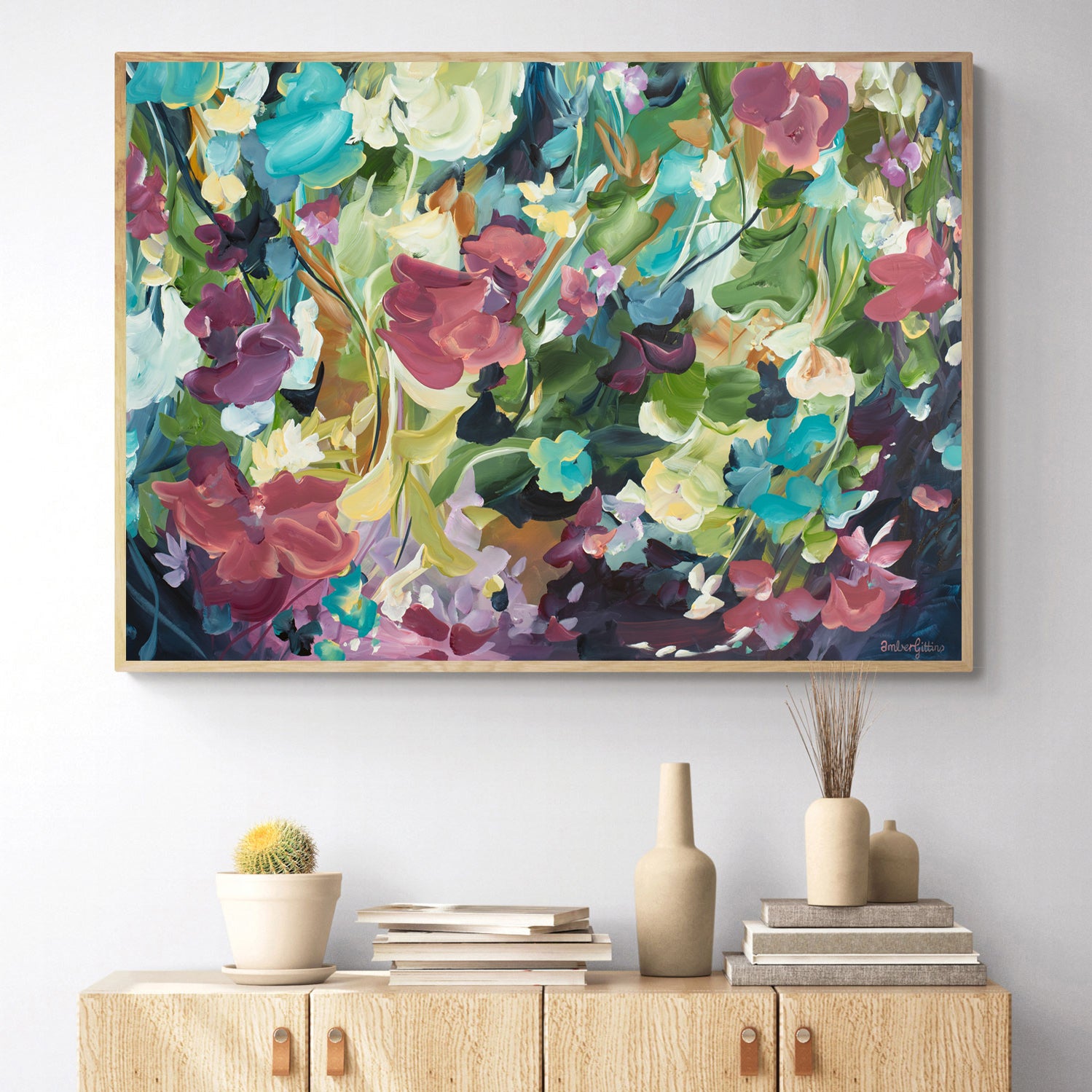 Colourful modern abstract floral wall art print. Expressionist contemporary style of floating flower petals and leaves. Framed in a natural frame hanging against a living room wall.