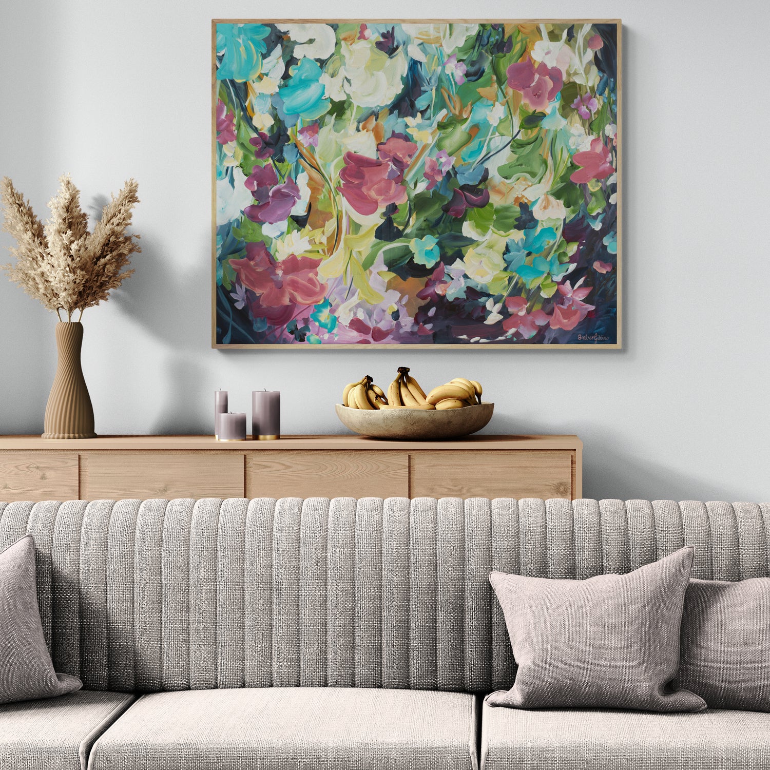 Colourful modern abstract floral wall art print. Expressionist contemporary style of floating flower petals and leaves. Framed in a natural frame hanging against a living room wall.