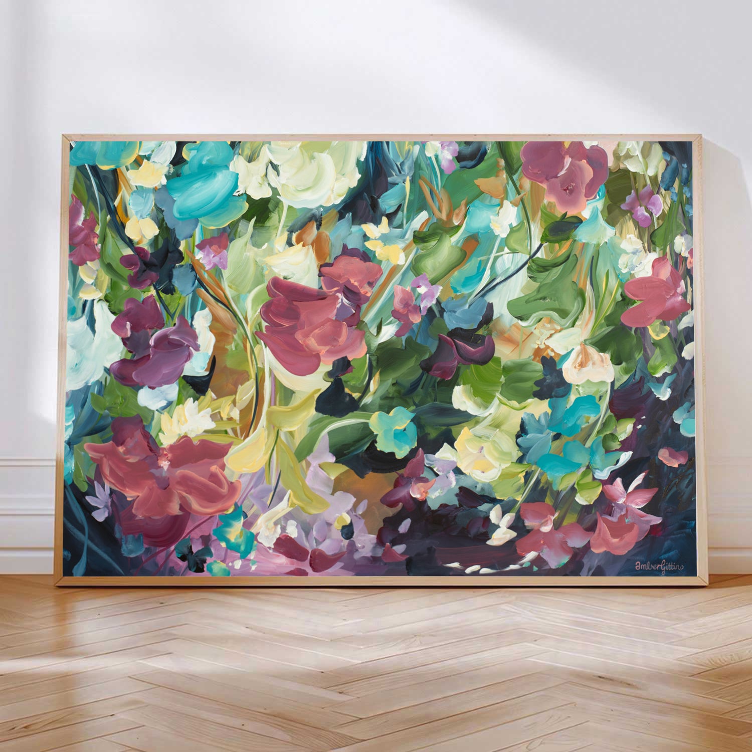 Modern colourful abstract floral canvas art print with a dark black background and colourful pink, red, aqua, green and yellow flowers. Framed in a natural frame and leaning against a wall.