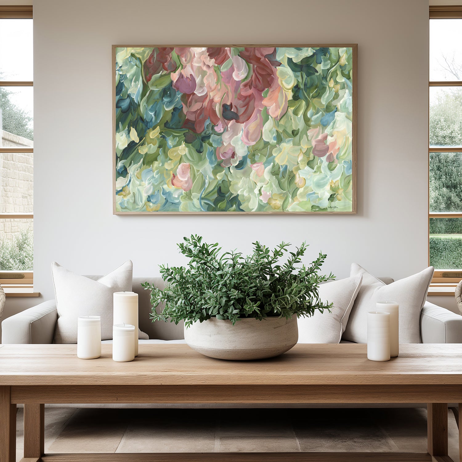 Modern impressionist abstract wall art print of organic round shapes layered like leaves and flower petals falling. Soft pastel green and pinks with pale yellow modern colour palette. Framed in a natural frame and hanging in a contemporary living room.