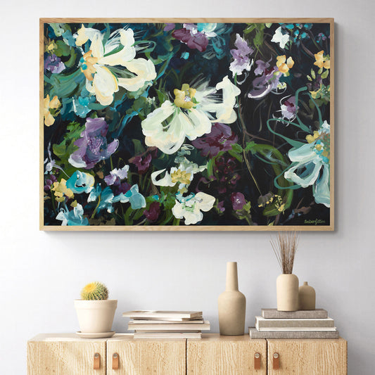 Dark and moody abstract flower  fine art canvas print with purple and white and yellow flowers. With a natural frame hanging against a wall.