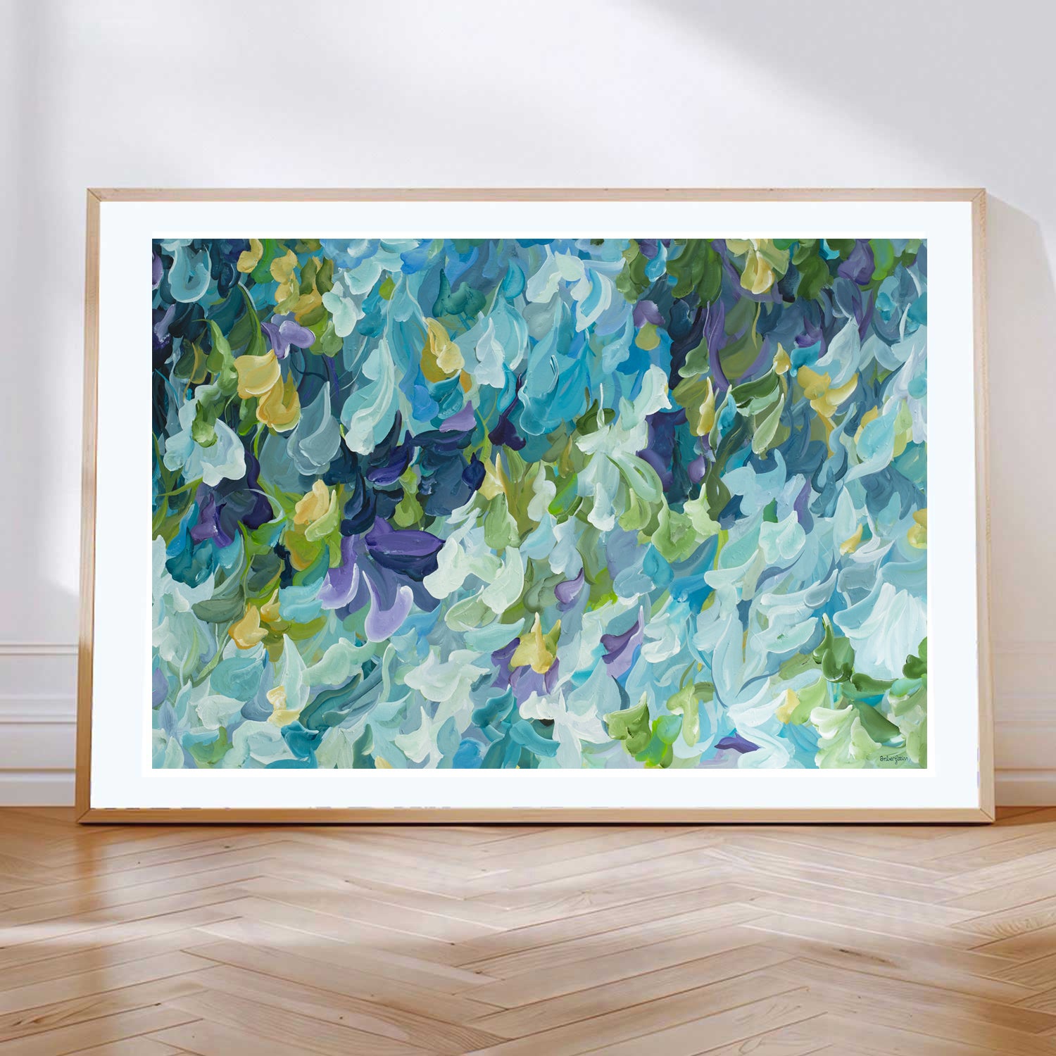 Modern blue, green and purple abstract impressionist wall art print in a minimal simple style. Falling petals and leaves in a garden. Framed in a natural frame, leaning against a lounge room wall.