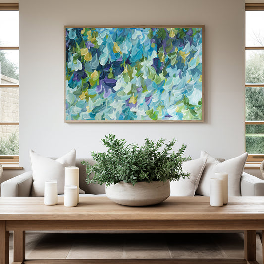 Modern blue, green and purple abstract impressionist wall art print in a minimal simple style. Falling petals and leaves in a garden. Framed in a natural frame, hanging against a modern neutral lounge room wall.