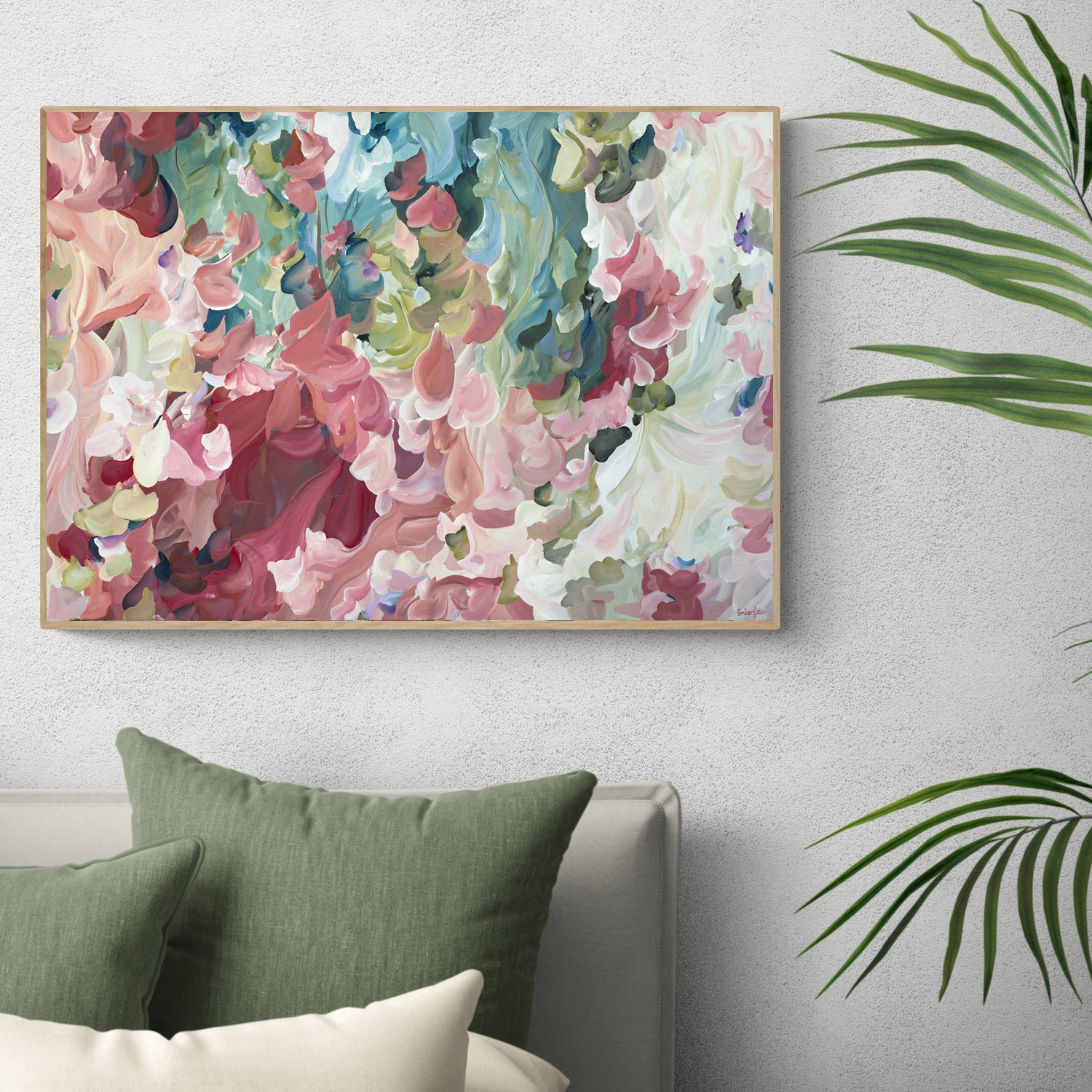 Pretty modern impressionist style abstract flower wall art print in pinks and greens. Framed in a natural frame and hanging against a living room wall.