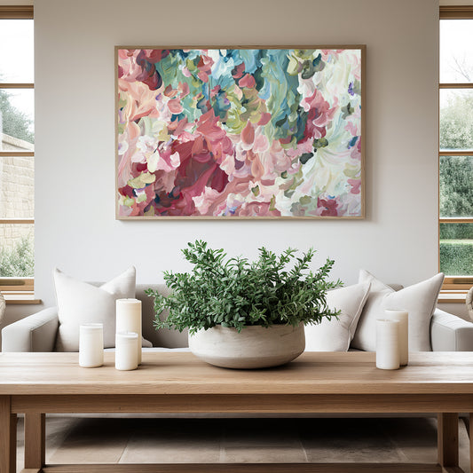 Modern impressionist style abstract flower art print in salmon pinks and greens hanging against a living room wall.