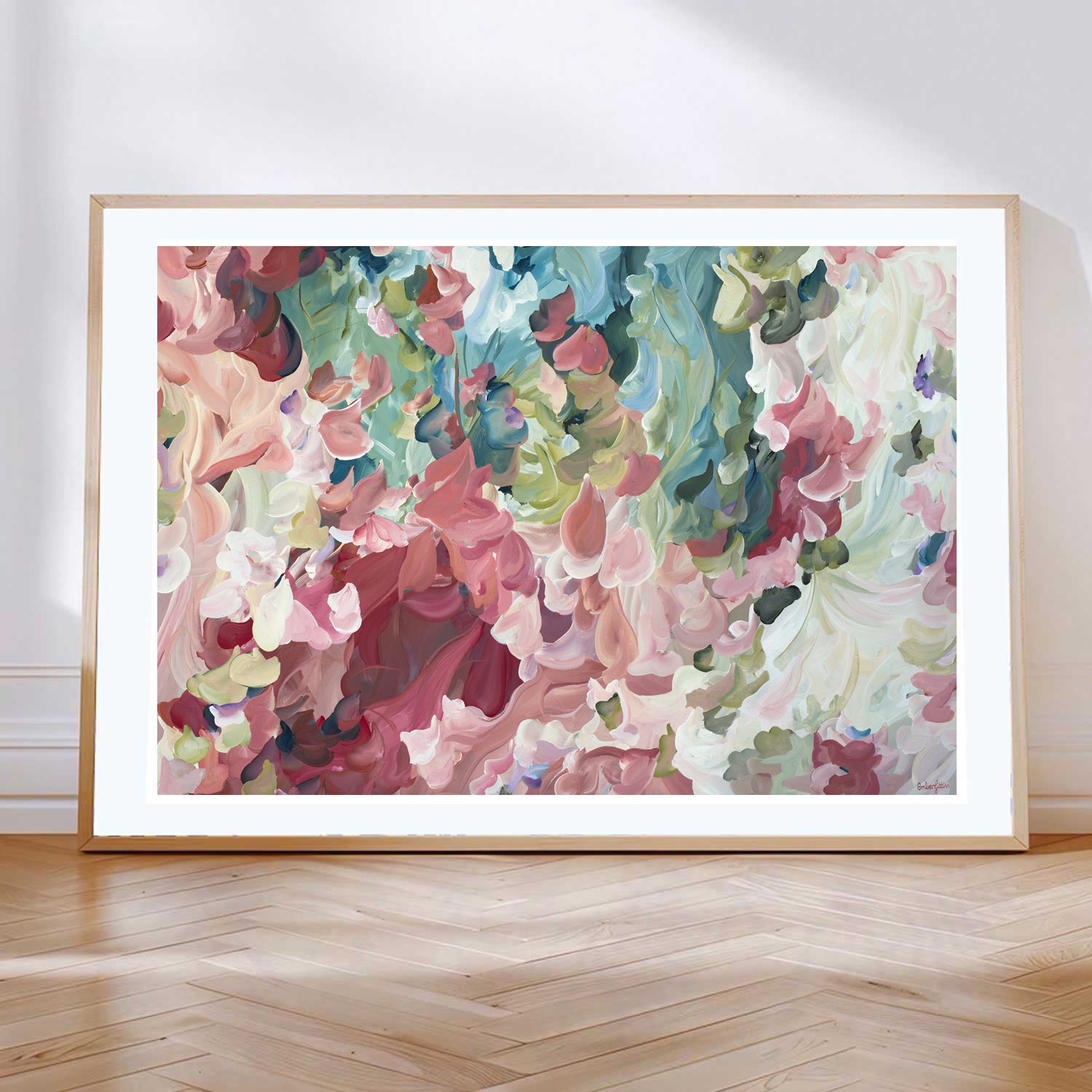 Modern impressionist style abstract flower art print in salmon pinks and greens leaning against a living room wall.