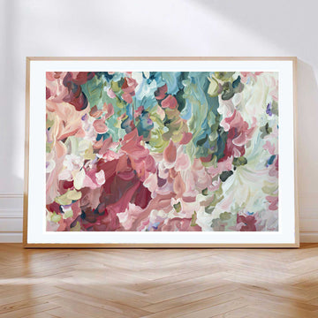 Modern impressionist style abstract flower art print in salmon pinks and greens leaning against a living room wall.