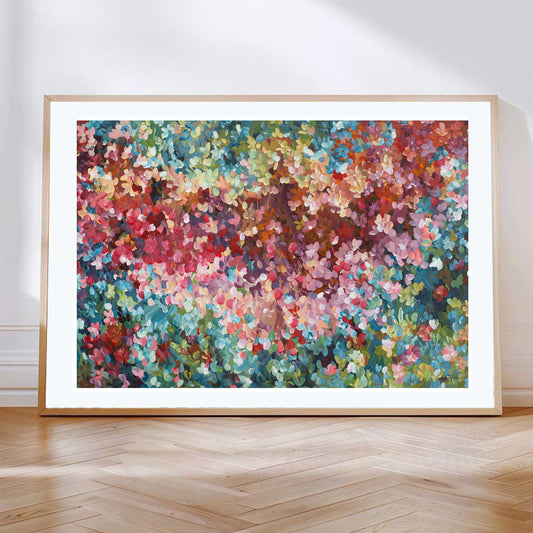 Colourful abstract fine art print. Dots and impressionist style representing small floral petals in nature. Framed in a natural frame, leaning against a wall.