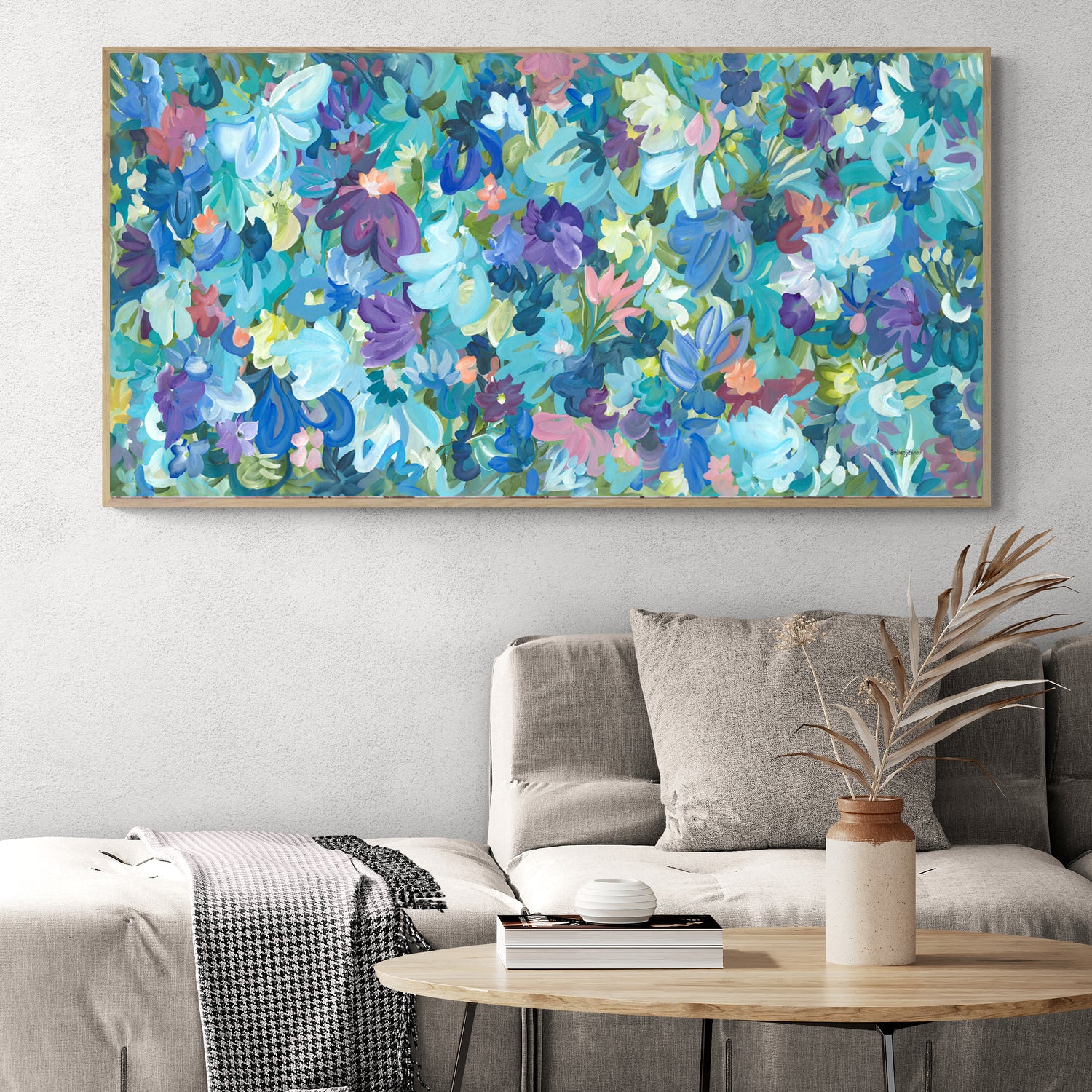 Colourful blue and purple abstract flower fine art print. Layers of flower petals and leaves in a modern impressionist style. Framed in a natural frame in a living room.