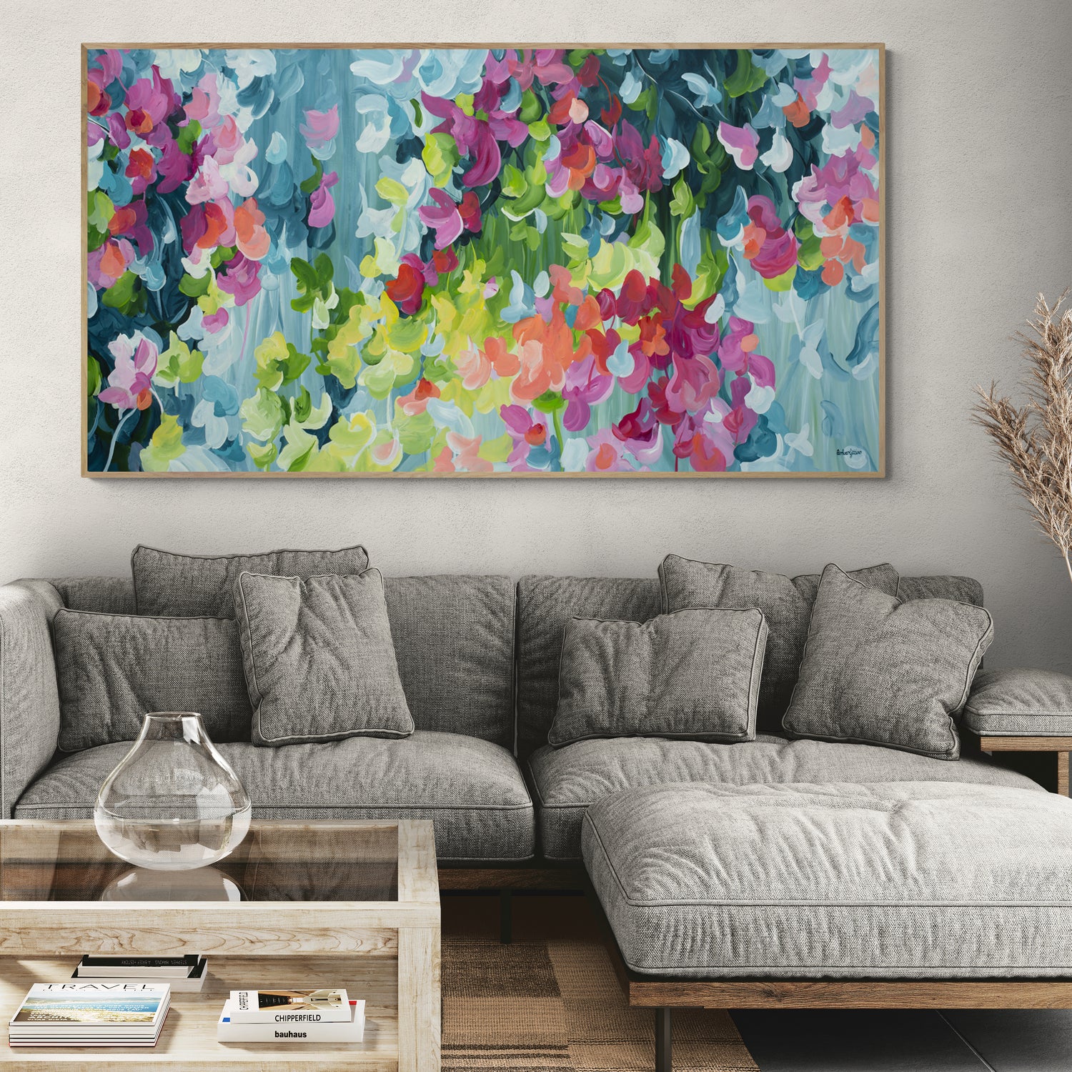 Gray sectional sofa in a living room with a colorful floral painting above it.