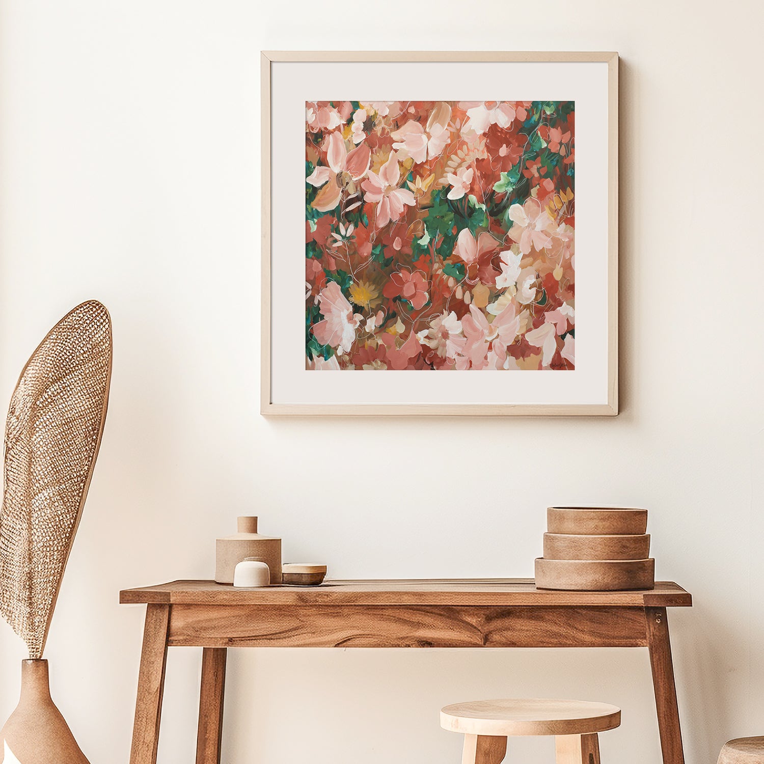 Framed pink and red floral fine art print above a wooden console table with decorative items.