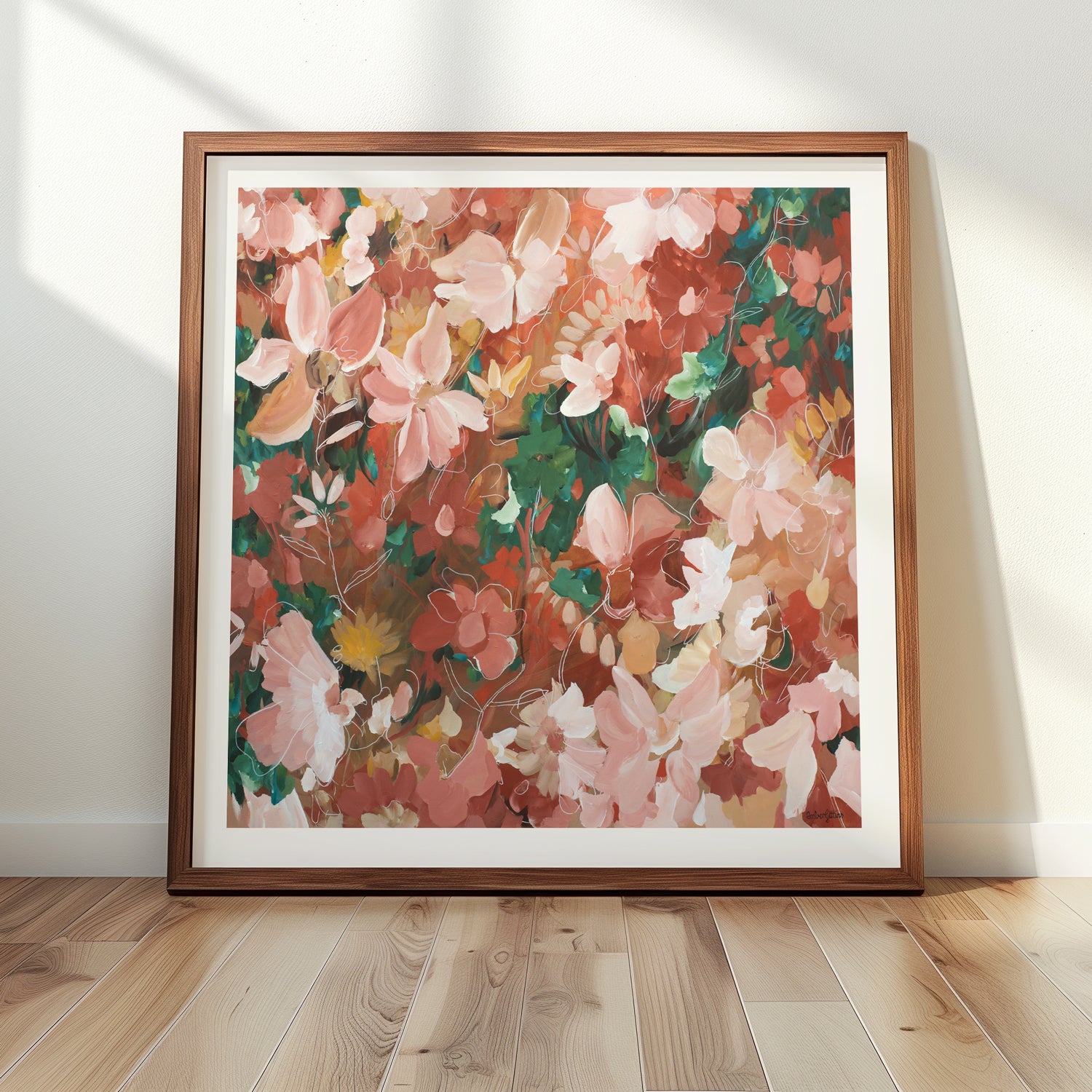 Framed pink and red abstract floral artwork on a wall with wooden floor