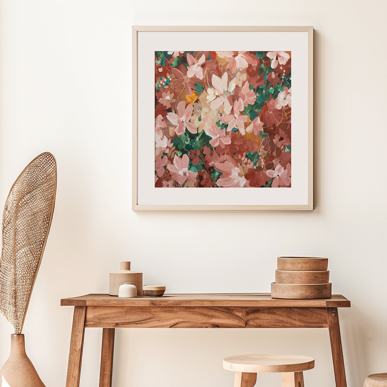 Framed red, pink and brown botanical art print on a wall above a wooden console table with decorative items.