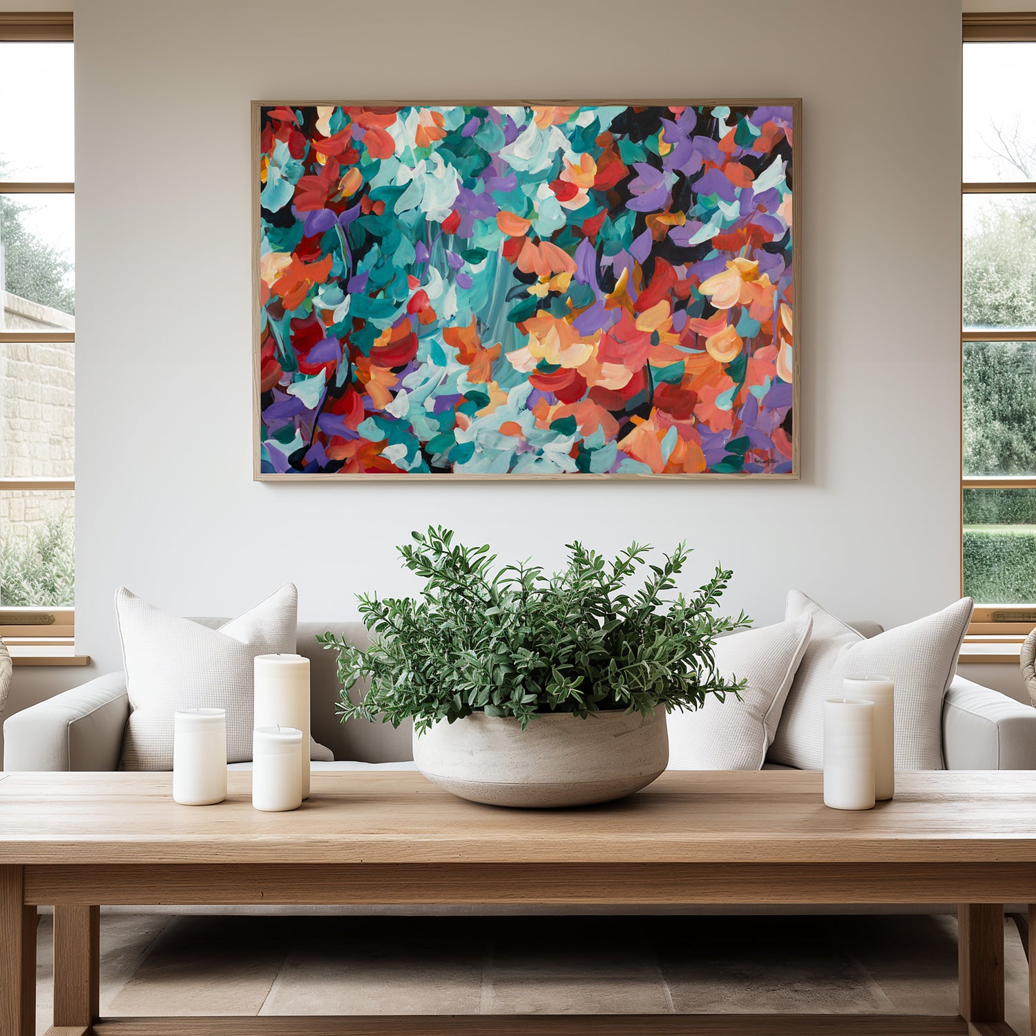 Bold and bright abstract art print in a modern abstract style of floating flower petals in red, orange, turquoise and purple. Hanging against a modern living room wall with a natural frame.