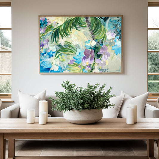 Abstract tropical  fine art canvas print of palm trees and an oasis with purple and light blue tropical flowers. With a natural frame hanging against a wall in a neutral modern living room.