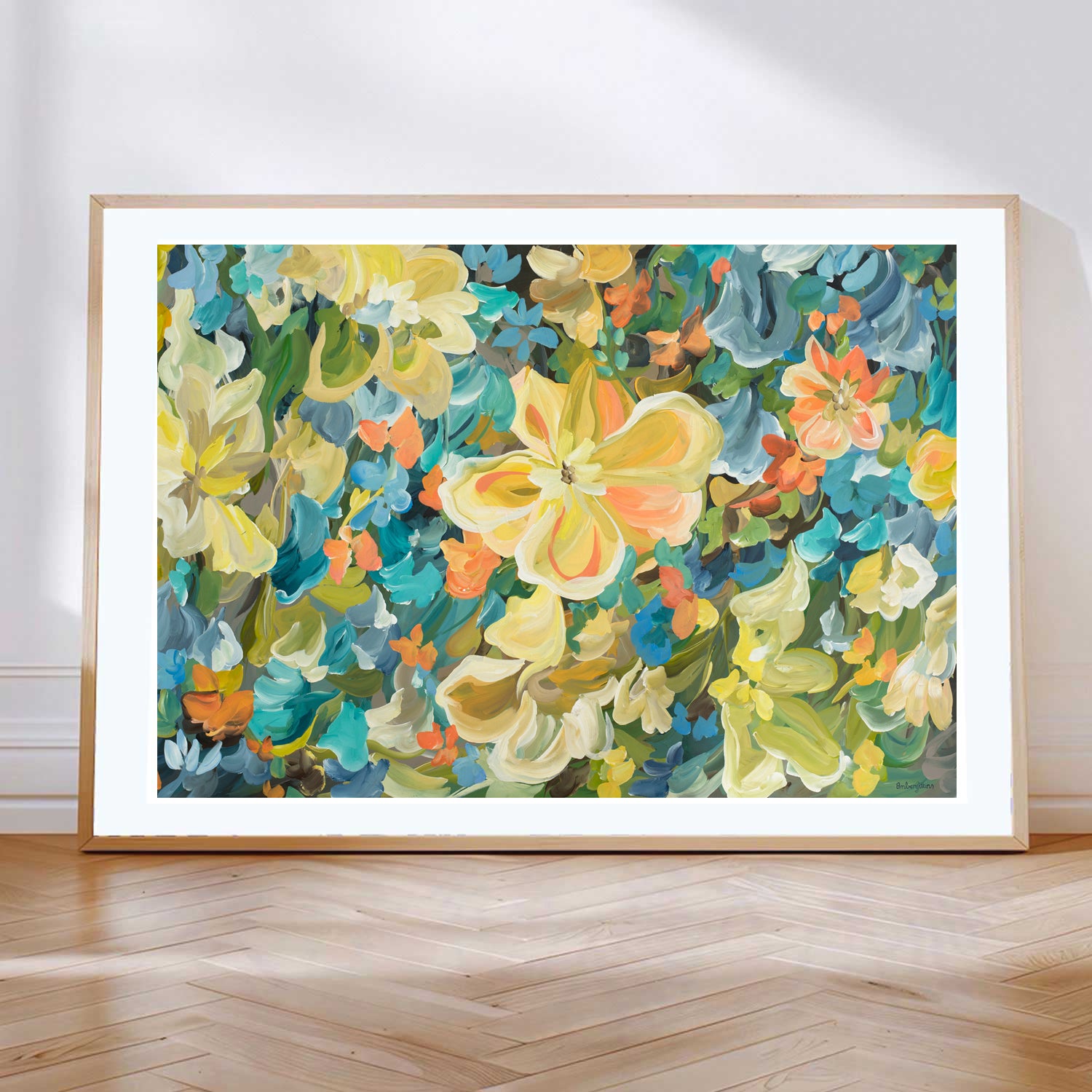 Modern abstract flower art print in bold yellow, blue, orange and green. Leaning against a living room wall with a natural frame.