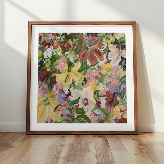 Natural and earthy wildflower abstract wall art print in neutral tones of brown, apricot, green, lilac and yellow. Layers of flower petals in a modern style. Framed in a natural frame , leaning against a living room wall.