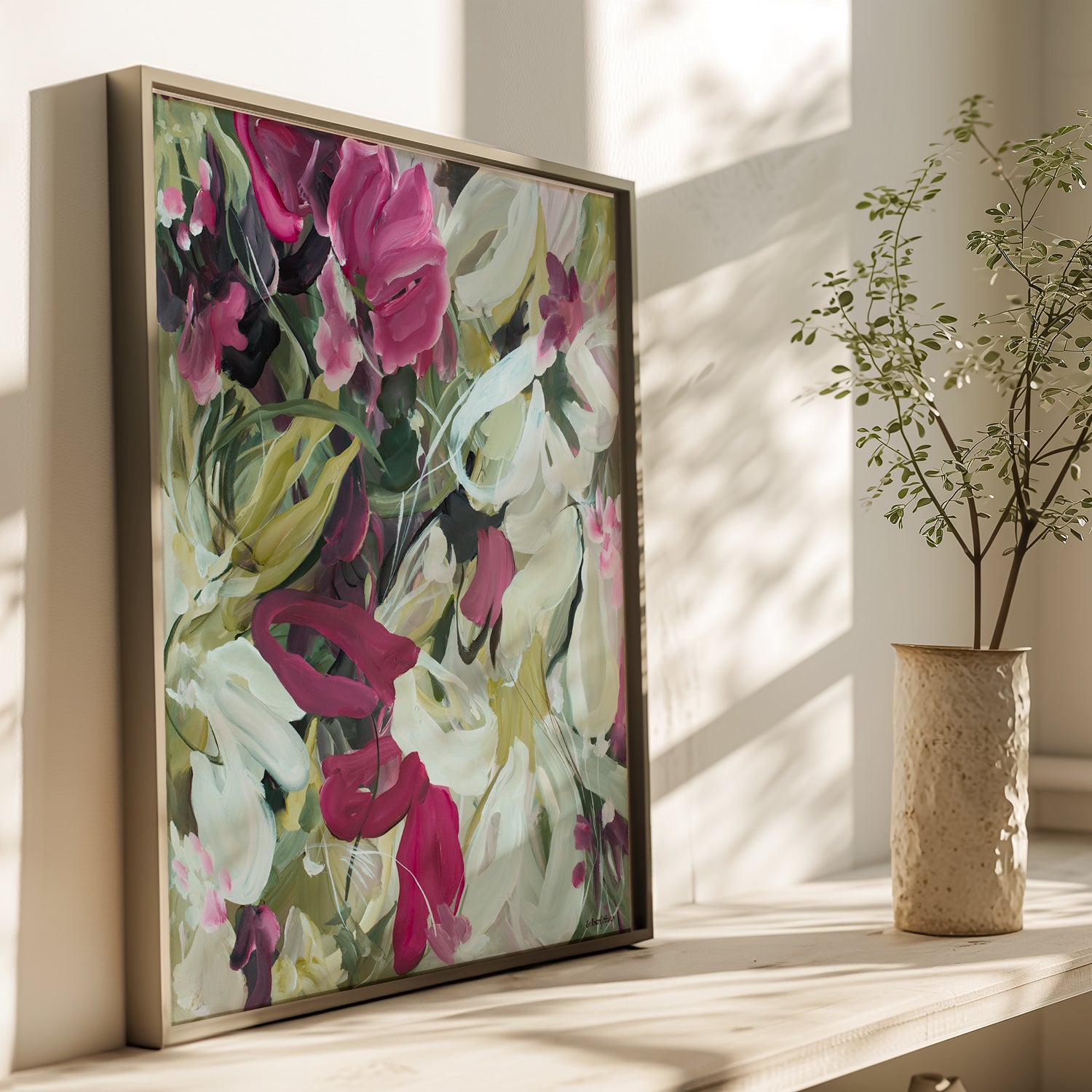 Modern wildflower fine art print in an expressive style in modern colour palette of burgundy, white and green. Abstract floral flowing shapes layered over each other. Framed in a natural bronze frame and leaning against a living room wall.