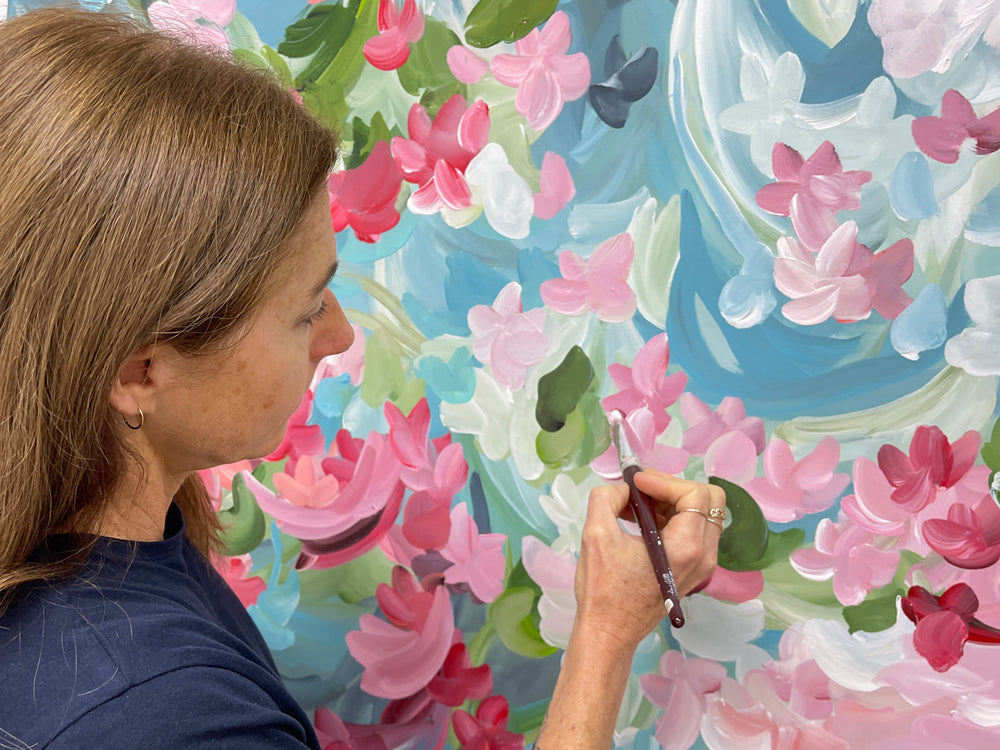 Artist Amber Gittins in her art studio with a flower abstract original painting
