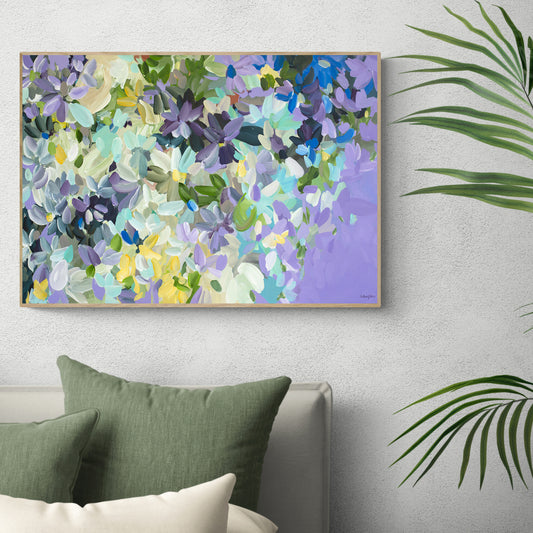 Colourful impressionist style abstract flower canvas art print in purple, spearmint and yellow. Framed in a natural frame hanging against a lounge room wall.