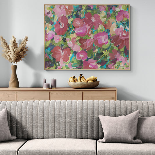Colourful modern red and pink abstract botanical wall art print in a contemporary impressionist style. Framed in a natural frame and hanging against a modern neutral living room wall.