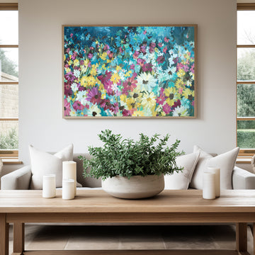Colourful daisy abstract flower fine art canvas print hanging in a living room with a natural frame.