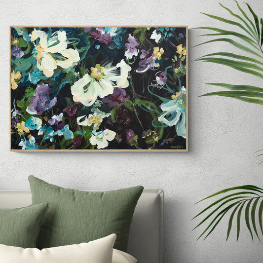 Dark modern abstract flower wall art print in black, blue and purple. Framed in a natural fame hanging against a living room wall.