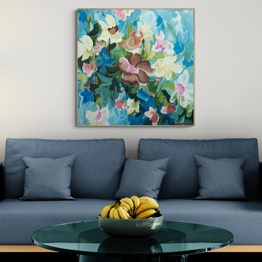 Living room with a blue sofa, floral painting, and a bowl of bananas on a table.