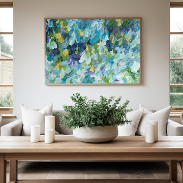 Modern blue, green and purple abstract impressionist wall art print in a minimal simple style. Falling petals and leaves in a garden. Framed in a natural frame, hanging against a modern neutral lounge room wall.