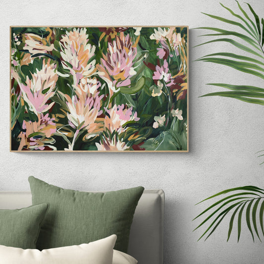 Colourful contemporary abstract protea flower wall art print in greens, pinks and warm orange yellow. Framed in a natural oak frame hanging against a living room wall.