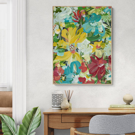 Bold, bright and colourful abstract flower art print in a modern style. Framed in a natural oak frame hanging against a living room wall.