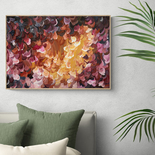 Bright and fiery red, orange and yellow abstract nature wall art print of falling leaves in nature. Framed in an oak natural frame and leaning against a living room wall.