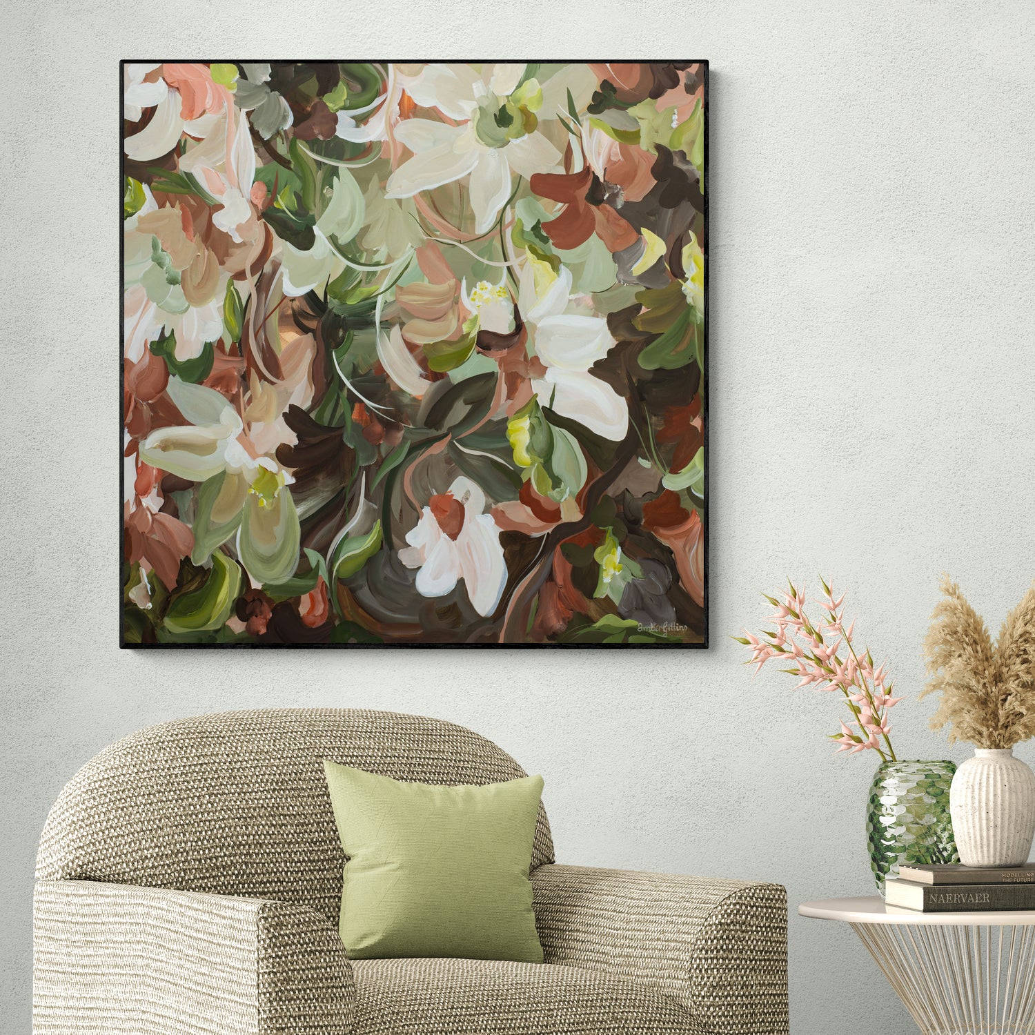 Natural coloured floral painting on a wall above a textured armchair with a green pillow.